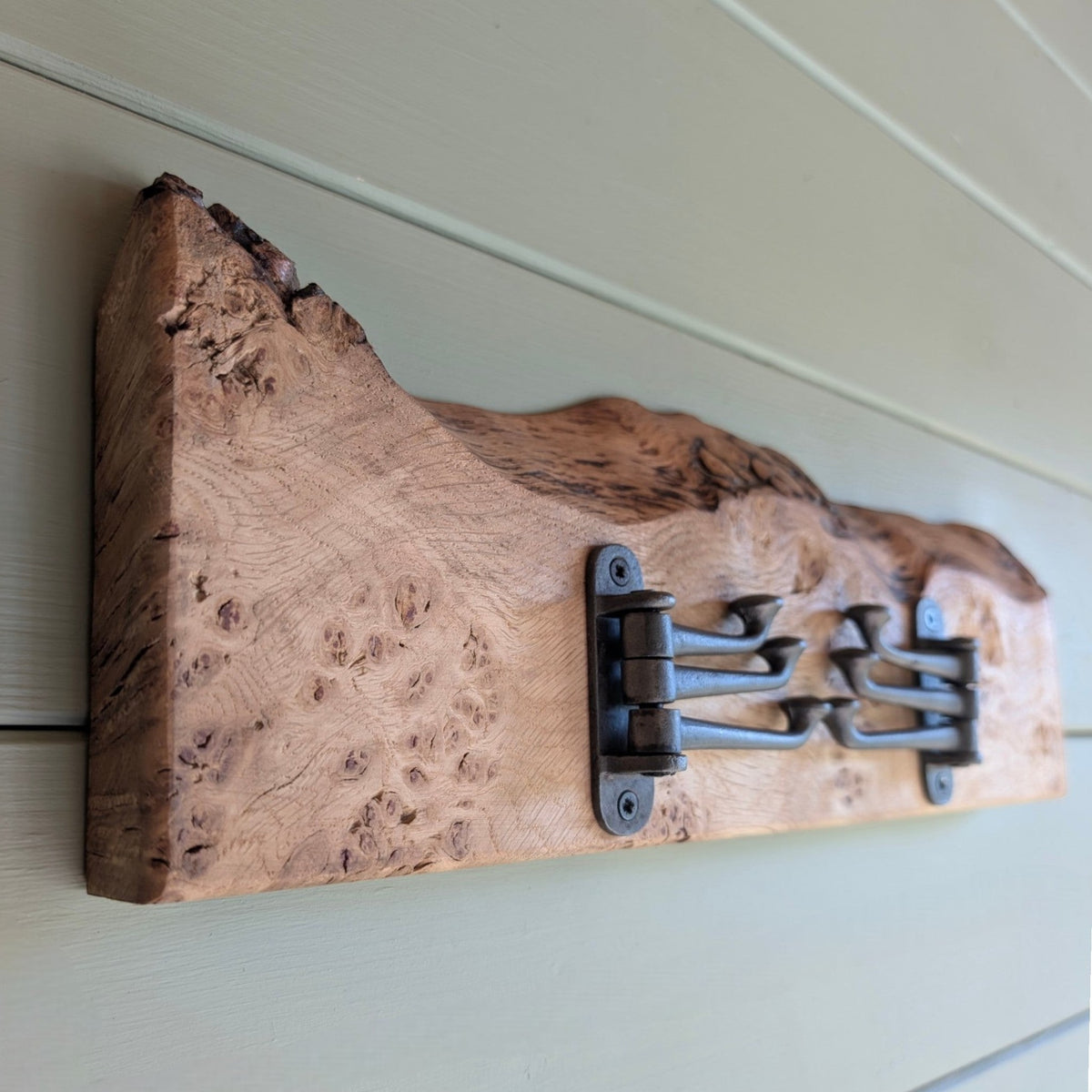 Cast‑iron hinge hooks with Pippy Oak / Burl Oak cat’s‑paw grain and live‑edge contour